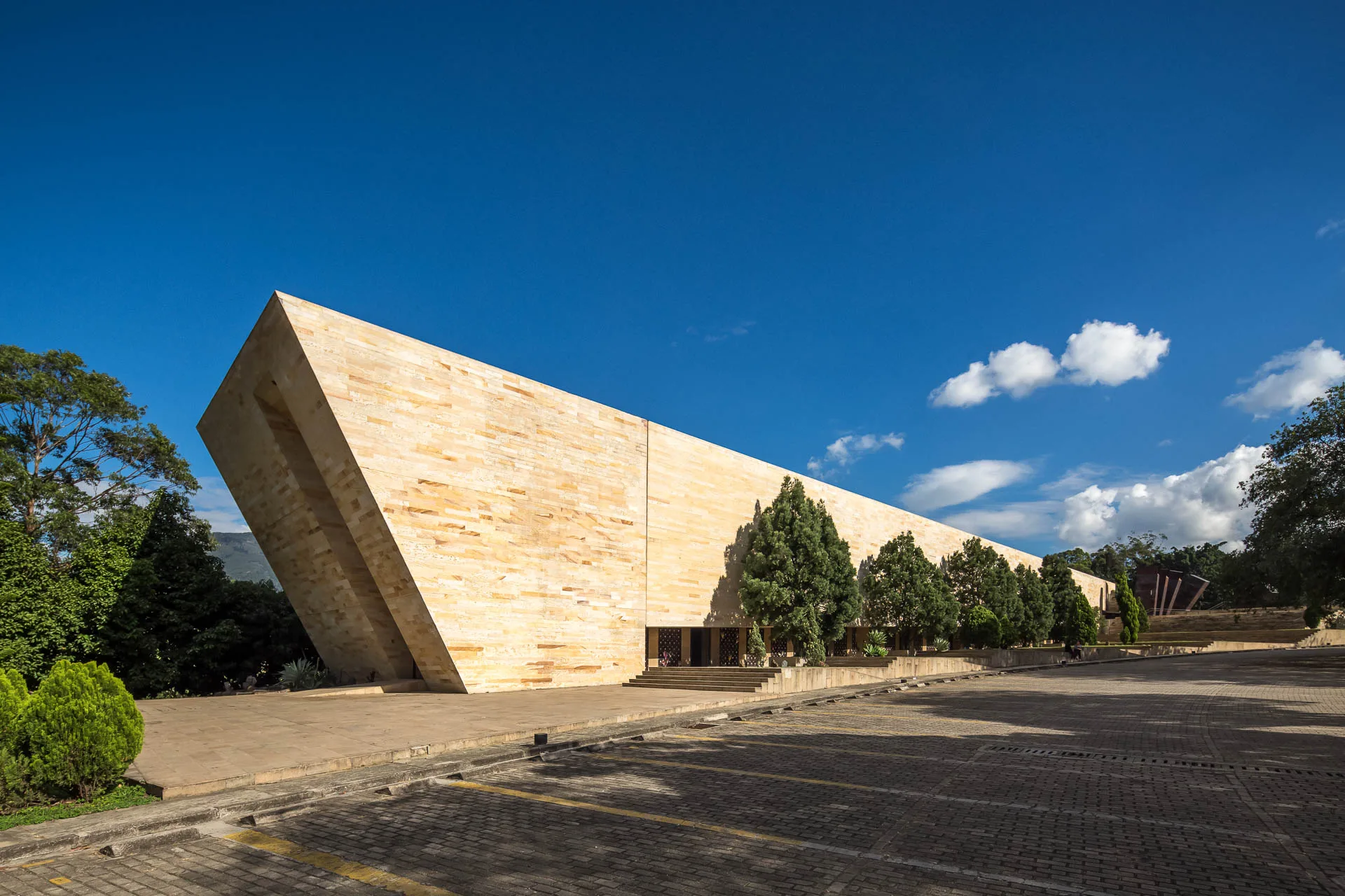 Fachada minimalista de concreto y cruz calada del Templo de las Cenizas en Medellín por +udeb.